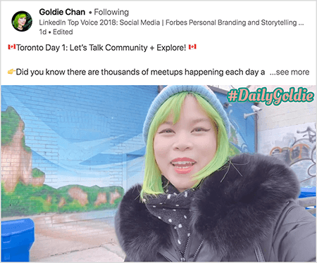 Dies ist ein Screenshot eines LinkedIn-Videos, in dem Goldie Chan ihre Reisen dokumentiert. Der Text über dem Video lautet "Toronto Day 1: Reden wir über Community + Explore!" Wussten Sie, dass jeden Tag Tausende von Meetups stattfinden?.. Mehr sehen". Das Video zeigt Goldie vor einem Wandgemälde auf einer Mauer. Das Wandbild zeigt einen strahlend blauen Himmel und braune Klippen, die mit hellem Grün bedeckt sind. Goldie erscheint von der Brust aufwärts. Sie ist eine asiatische Frau mit grünen Haaren. Sie trägt eine blaue Strickmütze und einen schwarzen Parka mit einem pelzigen Kragen. In der oberen rechten Ecke des Videos wird #DailyGoldie in Pfirsichtext mit einem grünen Umriss angezeigt.