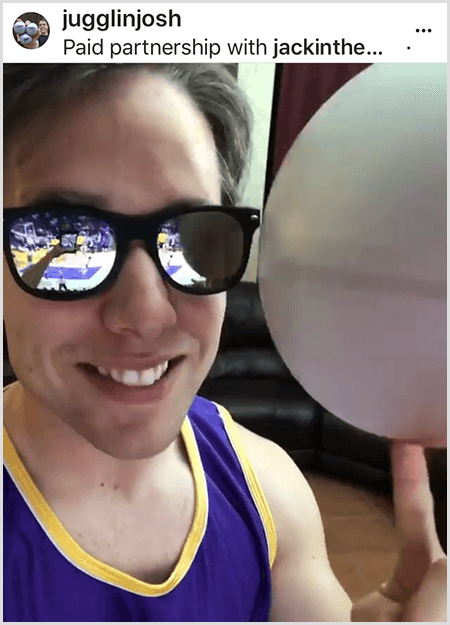 Josh Horton veröffentlicht ein Foto für eine Kampagne mit Jack in the Box und den LA Lakers. Josh trägt eine verspiegelte Sonnenbrille und ein Lakers-Trikot und lächelt in die Kamera, während er einen Ball dreht.